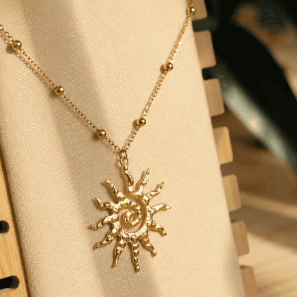 Collier Vaya doré en acier inoxydable avec pendentif soleil sur chaîne perlée.